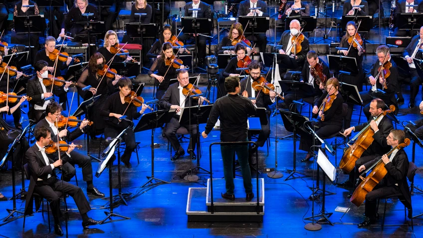 Herbert Pixner Projekt gemeinsam mit dem Tonkünstler-Orchester auf einer großen Bühne, Musiker mit traditionellen und klassischen Instrumenten.