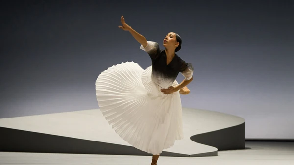 Tänzerin in schwarz-weißem Kleid bewegt sich auf grauer Bühne