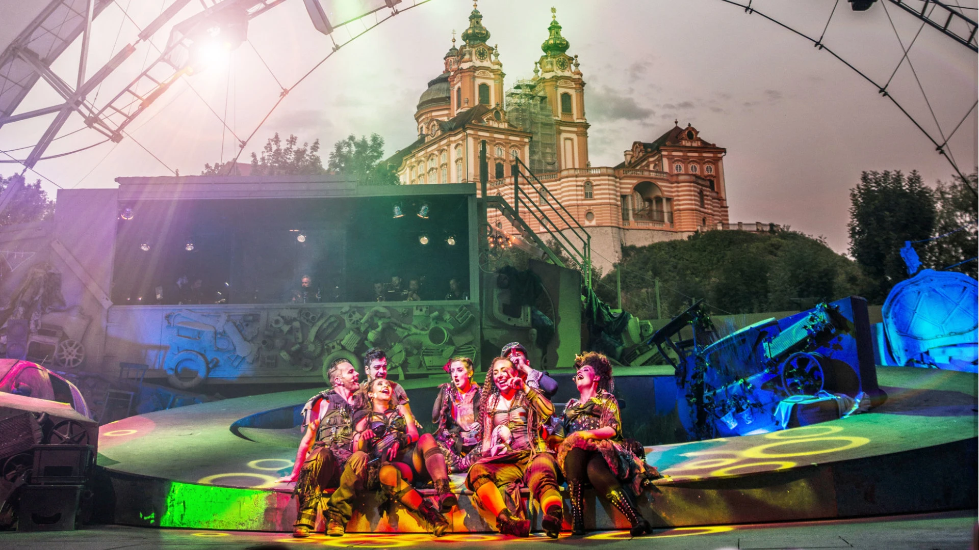 Bunt beleuchtete Theateraufführung im Freien mit Blick auf das Stift Melk in der Abenddämmerung.