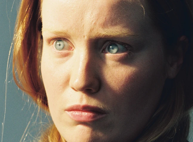 Nahaufnahme einer Frau mit blauen Augen und rotblonden Haaren mit hypnotisierendem Blick