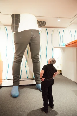 Besucher blickt in der Ausstellung an langen Beinen des Ausstellungsdesigns nach oben.