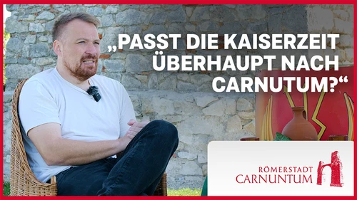 Thumbnail für den Videocast mit abgebildeten Daniel Kunc der fragt "passt die Kaiserzeit überhaupt nach Carnuntum?" Antwort: "Herst natürlich" 