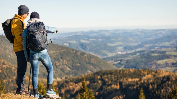 zwei Personen blicken vom Berg ins Tal hinunter