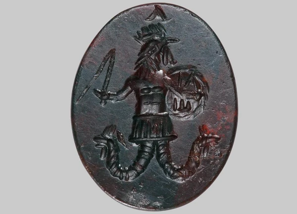 Magical gem in black, depicting a male figure with a rooster's head and serpent's legs, holding a whip and a shield