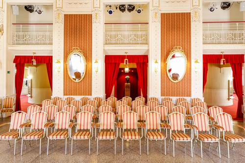 Festlicher kleinerer Saal mit zahlreichen Stühlen, im Hintergrund zwei Wandspiegel