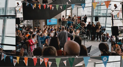 Photo from the BIG BANG Festival showing children singing in the colourfully decorated Festspielhaus St. Pölten.