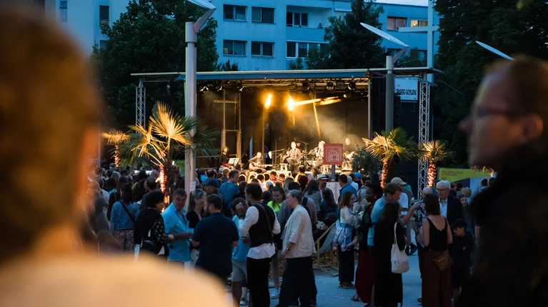 Foto vom Festival "StadtLandFluss", frühe Abendstimmung der Menschenmenge auf dem Festspielhaus-Vorplatz.