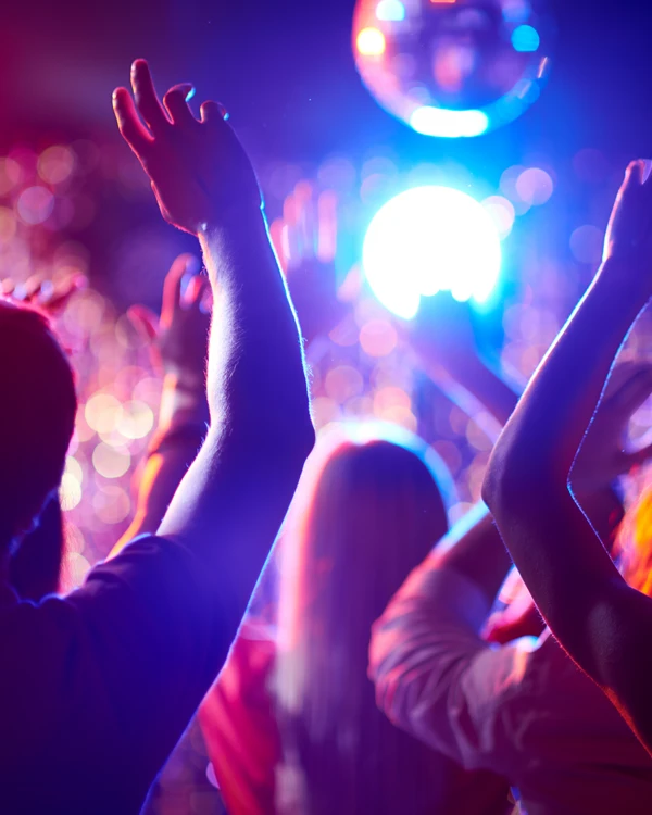 tanzende Menge, abgebildet von hinten. Von der Decke hängt eine Discokugel.
