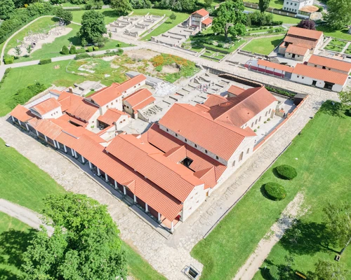 Aerial photograph of the houses in the Roman quarter. They are stone houses with red roofs surrounded by green meadows.