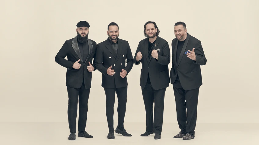 Vier Männer in schwarzen Anzügen vor weißem Hintergrund